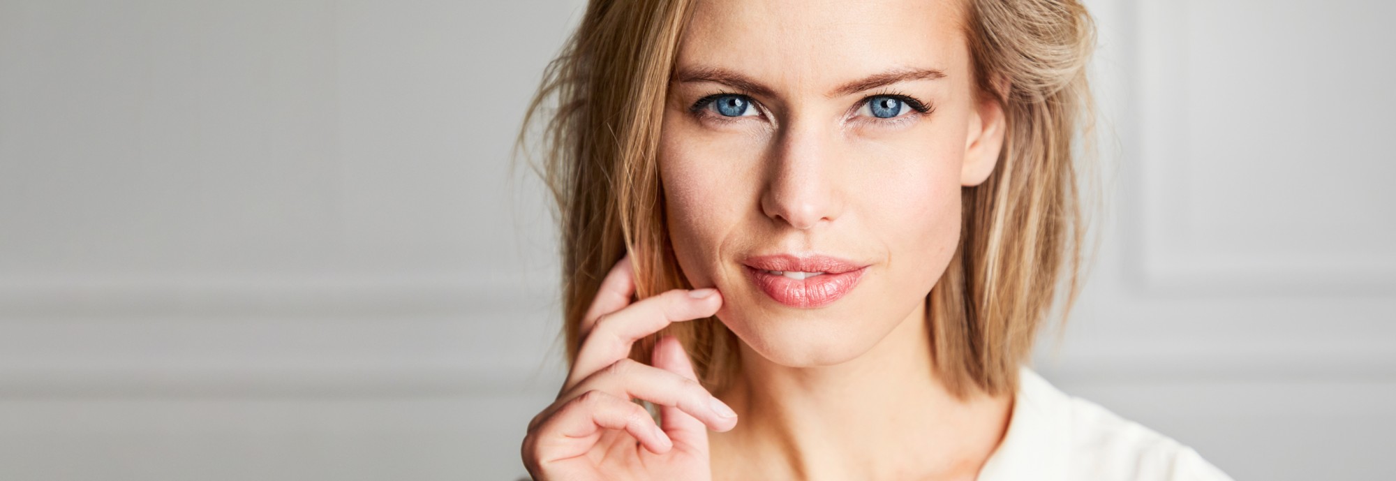 A woman receiving a dermal filler injection to her lips from a practitioner wearing blue gloves, illustrating the procedure.