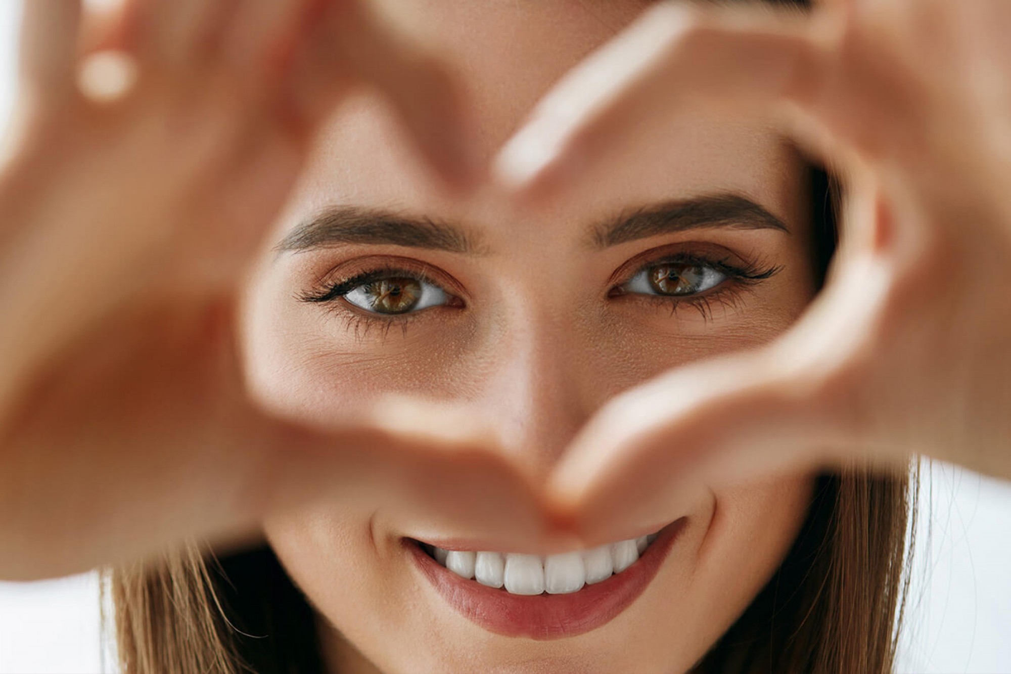 Happy patient making a heart with hands, clear skin