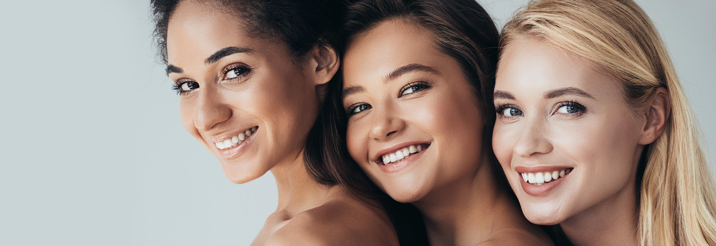 Three smiling women with diverse skin tones, showcasing their radiant healthy skin, exemplify the expert skincare provided by Springs Dermatology MD.